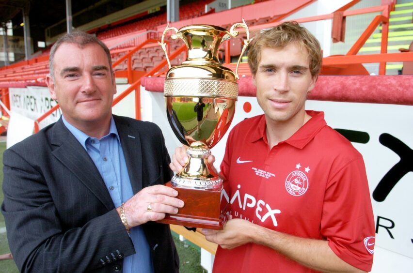 Jim Geddie and Russell Anderson holding a trophy at Pittodrie 