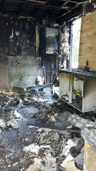 The kitchen is unrecognisable following the fire, with debris strewn on the floor and the walls covered in soot.