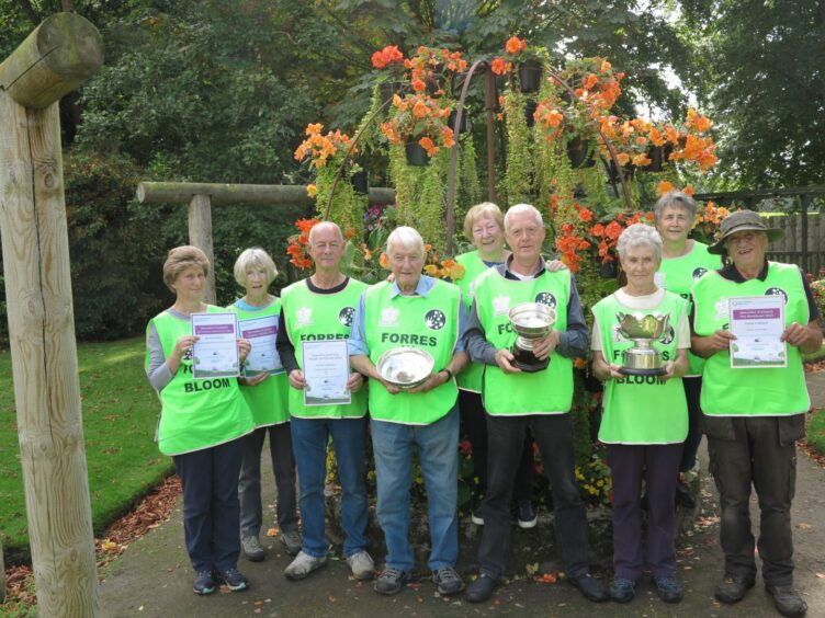 Forres in Bloom volunteers wearing neon green vests holding their Keep Scotland Beautiful awards