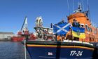 Cal Reed and Grant Bruce at Aberdeen Lifeboat Station holding a Scottish and Ukrainian flag.