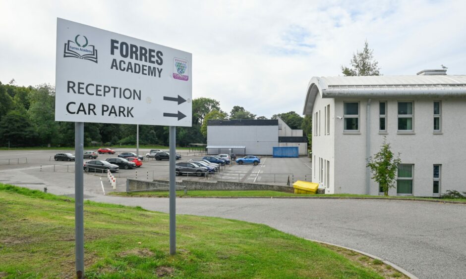 View of Forres Academy buildings with sign in foreground pointing to reception and car park.