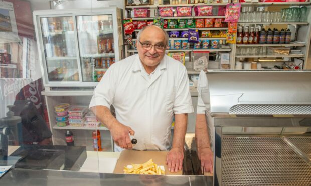 Michael Miele putting salt and vinegar on chips behind the counter at the Northern Fish Restaurant.