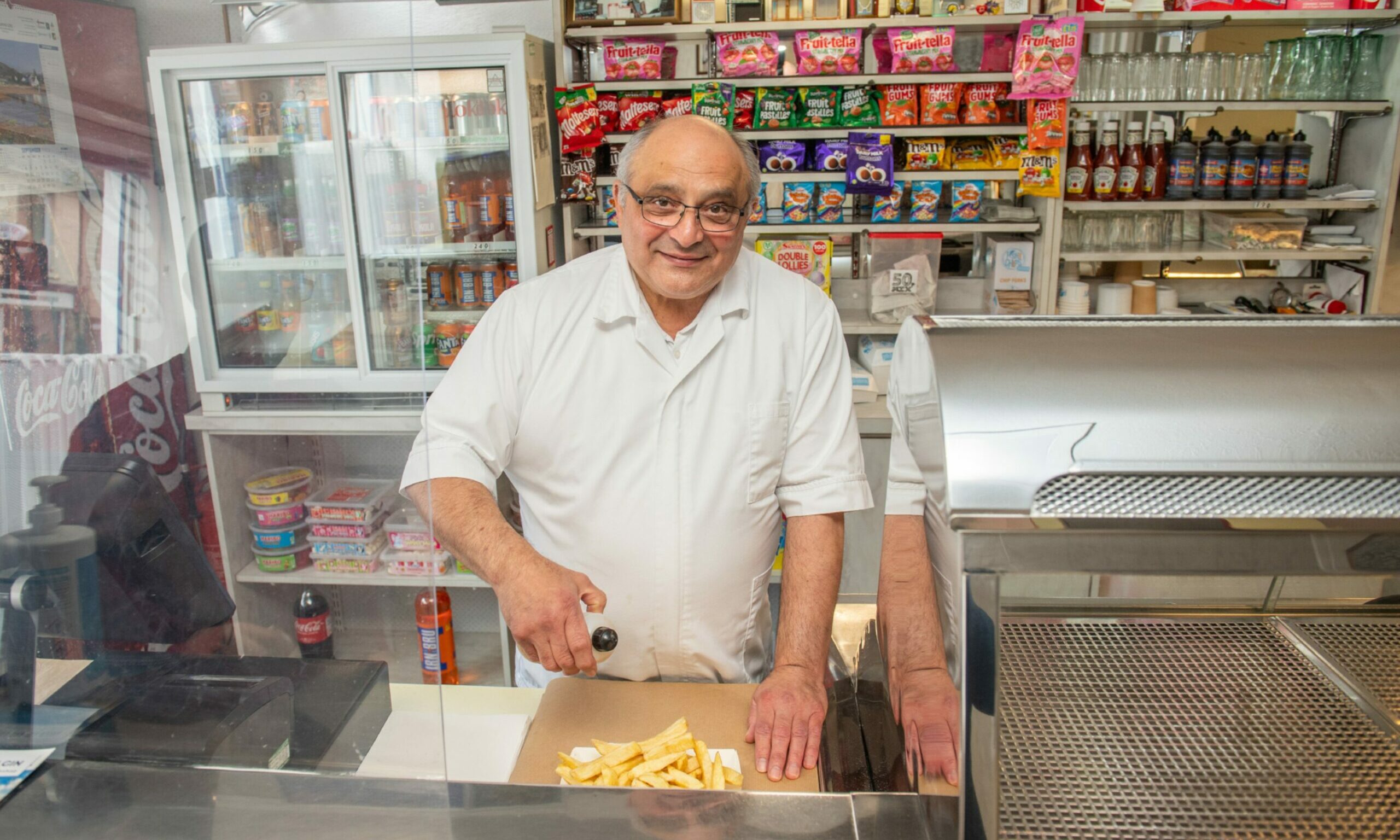Michael Miele putting salt and vinegar on chips behind the counter at the Northern Fish Restaurant. 