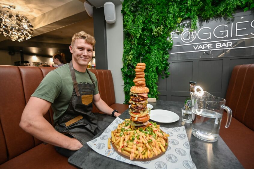 Someone posing with the Elgin's Humble Burger challenge untouched in front of him