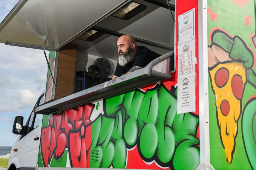 Mr Reid gazes out the serving hatch of their existing pizza van. 