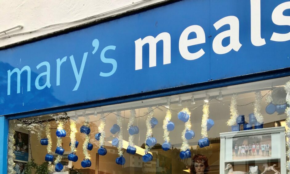 The shop window of Mary's meals charity shop in Oban featuring their signature blue paint work.