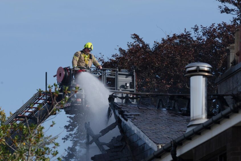 A firefighter using a hose reel jet to extinguish the fire at Albyn Place in Aberdeen 