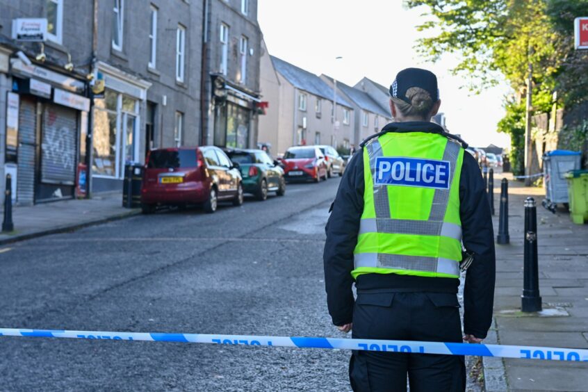 A police officer stands guard at a police line after an incident in Spital in Aberdeen. 