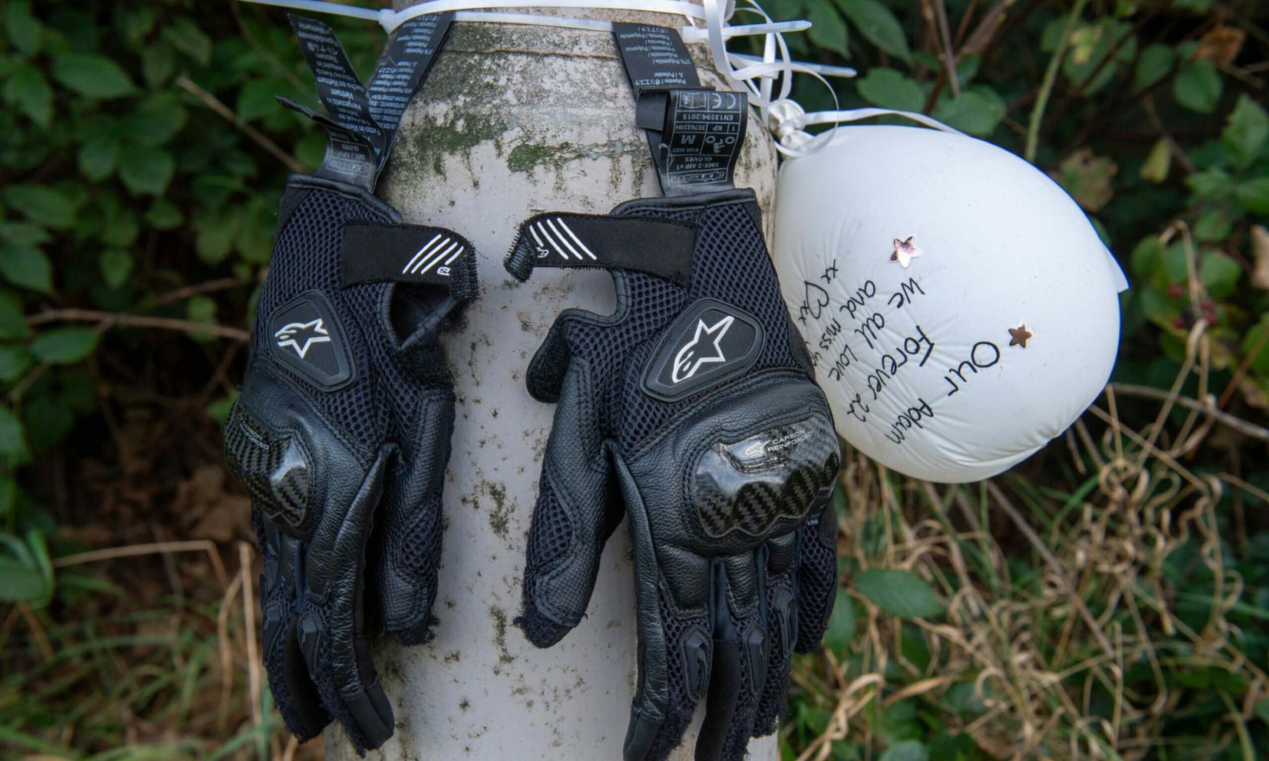 Bikers gloves and a balloon tied up to a lamppost.