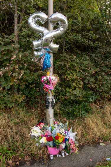 Balloons, with the age of 22, and flowers left at roadside.
