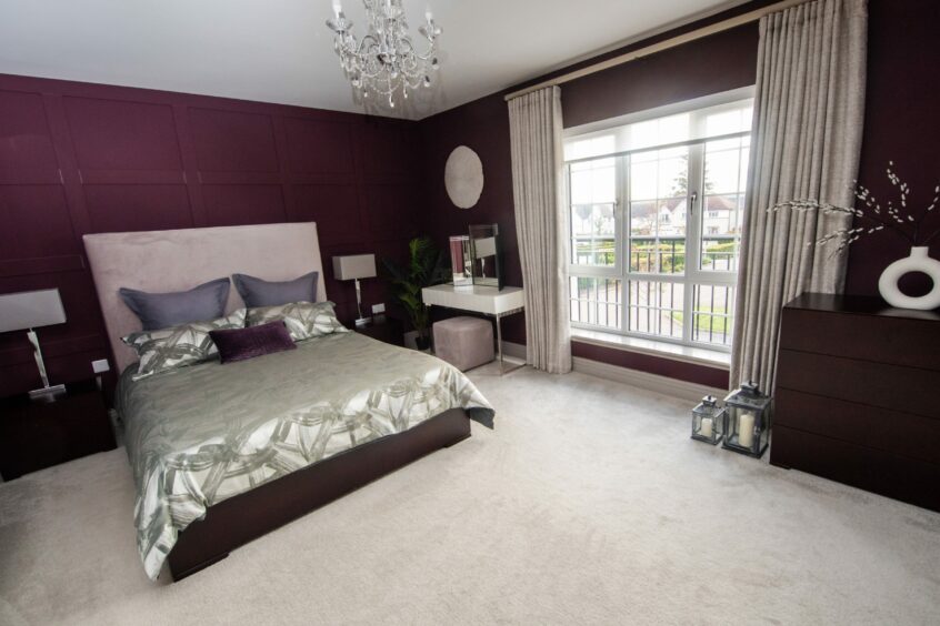 The bedroom in the home in Cults, with a double bed, cream carpet and deep purple walls