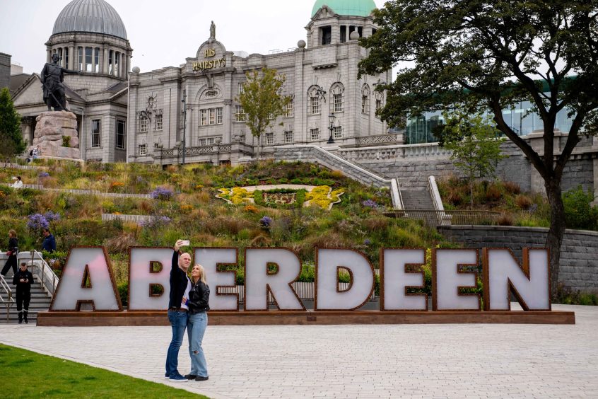 Couple take a selfie in front of Aberdeen letters 