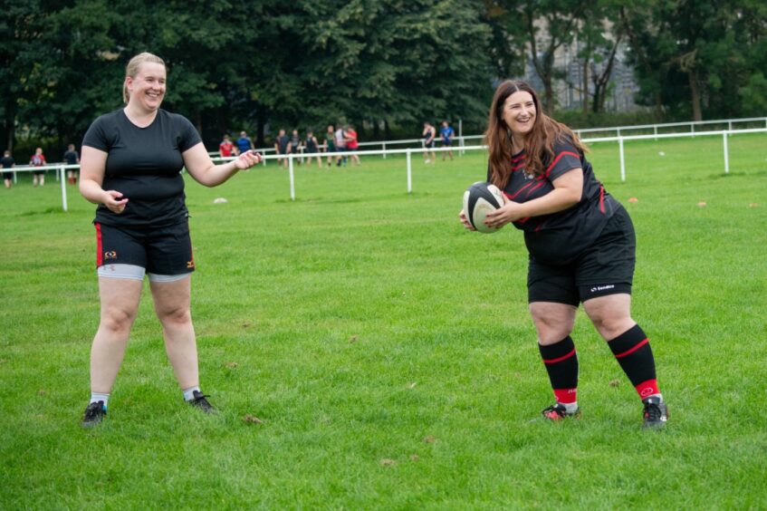 Members of the women's rugby club in Aberdeen smiling during a game.