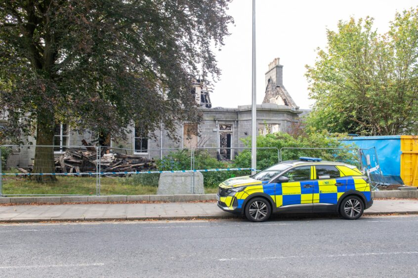 Police car parked outside damaged building on Albyn Place 