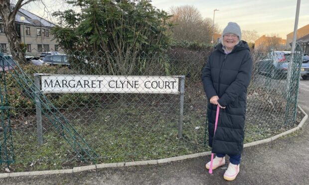 Margaret Clyne by the sign of the street named in her honour.
