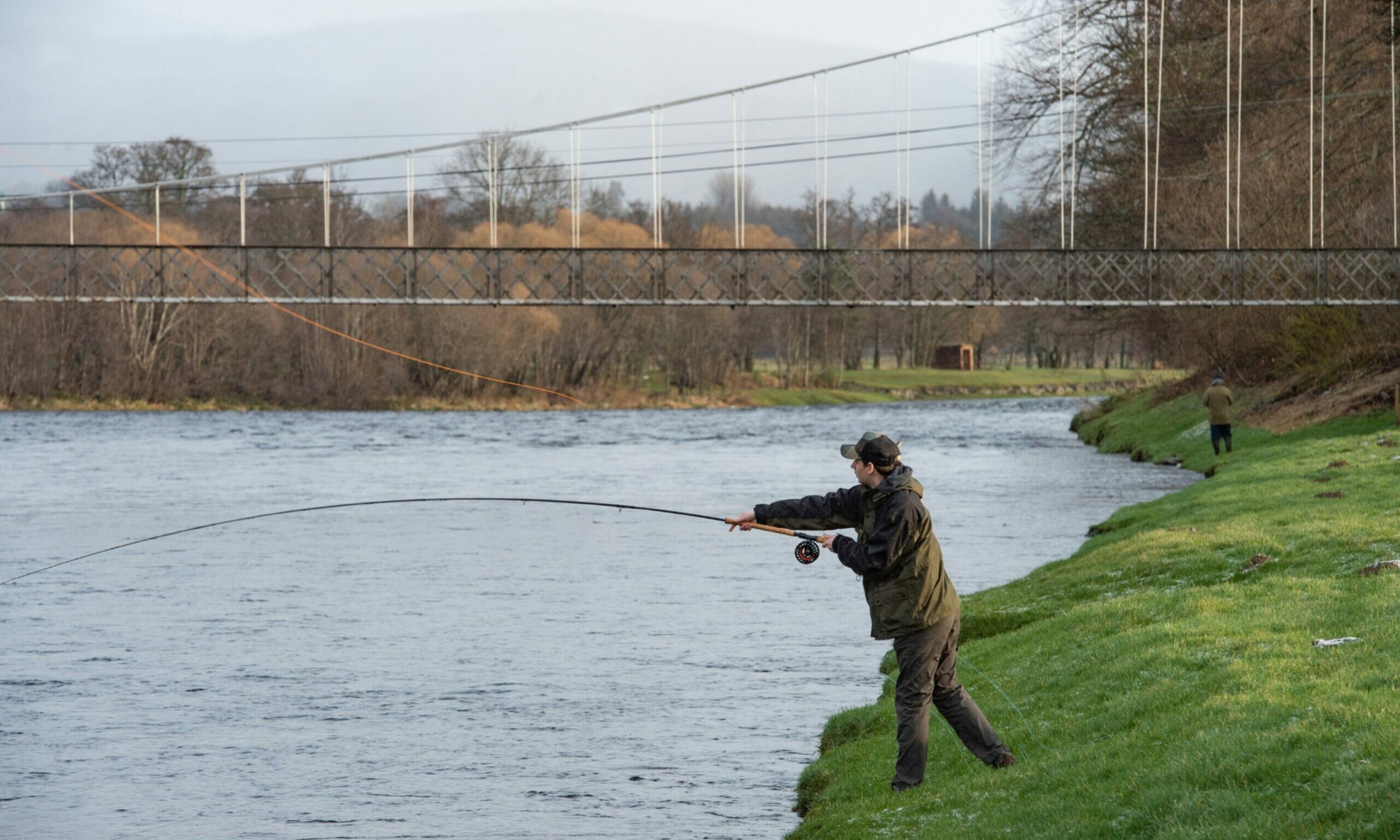 Lone angler casting line into River Spey on banks in Aberlour.