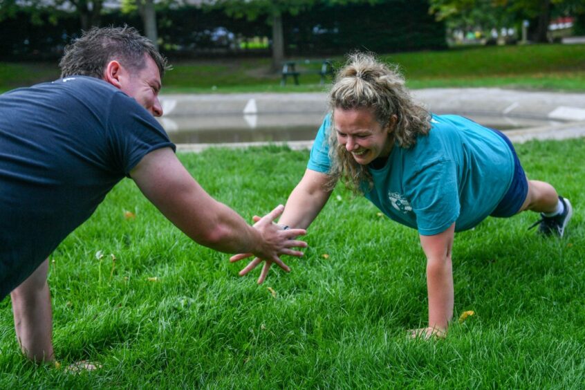 Tom and Alice show clients how to perform a high-five push up during a fitness class in Aberdeen.
