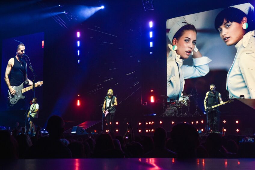 Busted playing at P&J live, clips from the Air Hostess music video are playing on the screen behind them