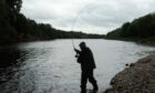 Silhouetted angler on River Spey casting a line.