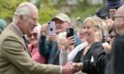 People take pictures of King Charles on mobile phones during Tomintoul visit.
