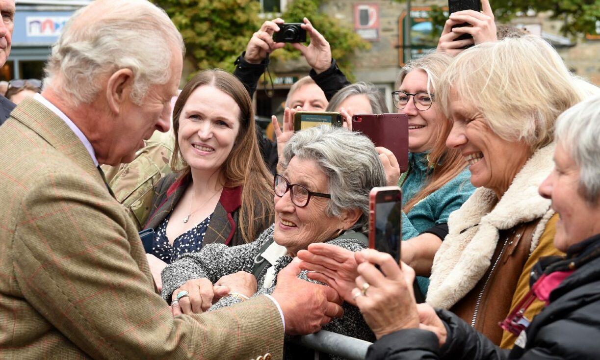 King Charles meets a lady with grey hair on a visit to Tomintoul. 
