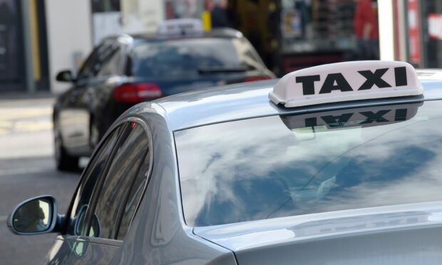 A silver car with a taxi sign on it at Inverness taxi rank.