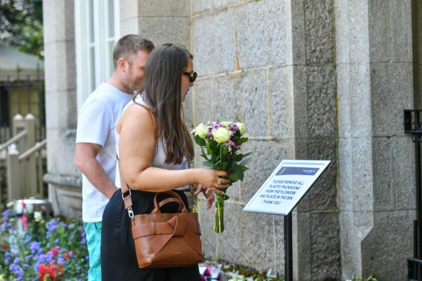 A couple leave flowers for the Queen at Balmoral on first anniversary of her death