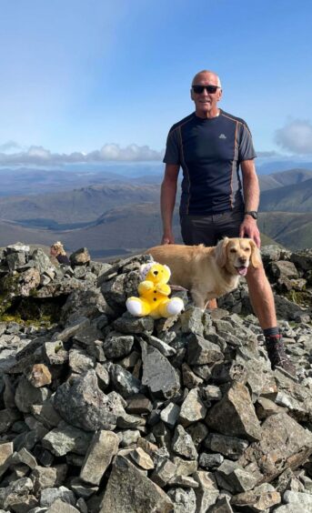 Man and dog standing at top of Munro.