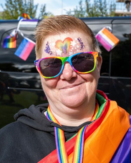 Moray Pride attendee with rainbow sunglasses and face paint.