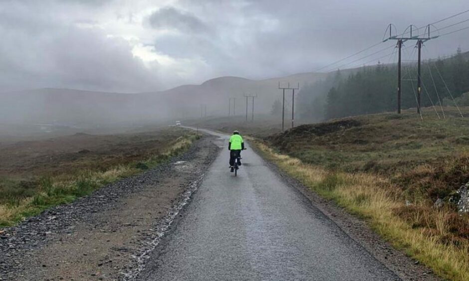 Peter Langford cycling amidst dark clouds during the last leg of his charity cycle from Lands End to John O'Groats.