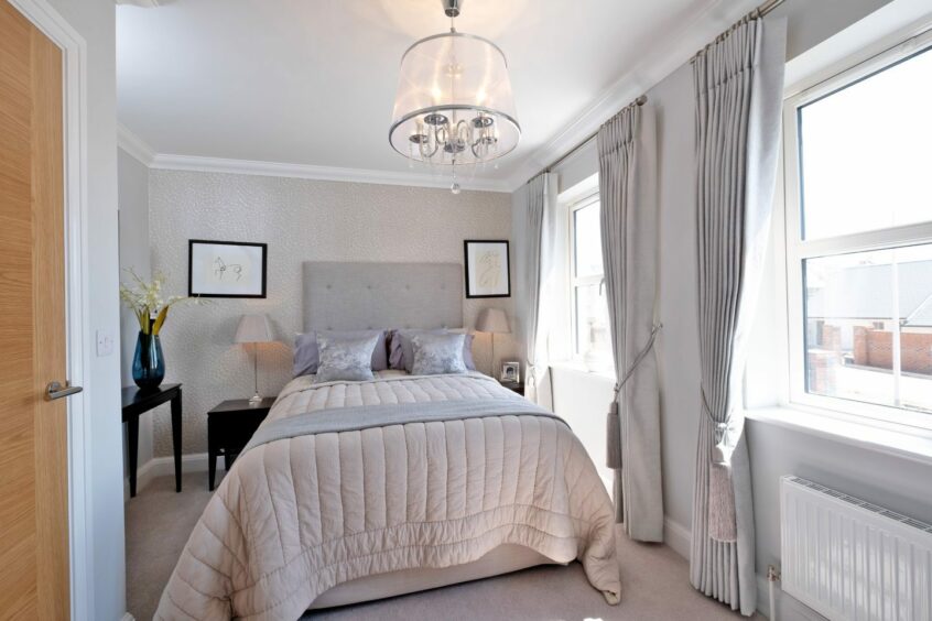 A bedroom with two windows and light grey colour scheme