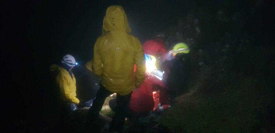 Mountaineers navigate by torch light amidst bad weather.