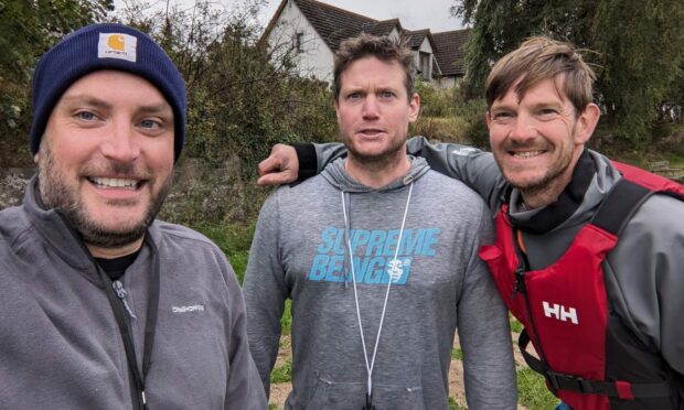 Edd Darber, James Greagg, and Darren Thompson wearing paddleboarding clothing smiling at camera.