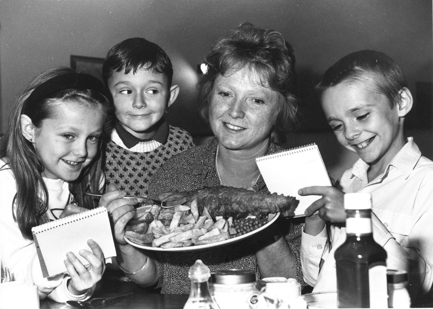 Primary 5 pupils Kerry McDonald, George Webster and Steven Forbes with teacher Jeanette Andrews holding a plate of fish and chips at the Ashvale Restaurant after completing their project on fishing in 1990.