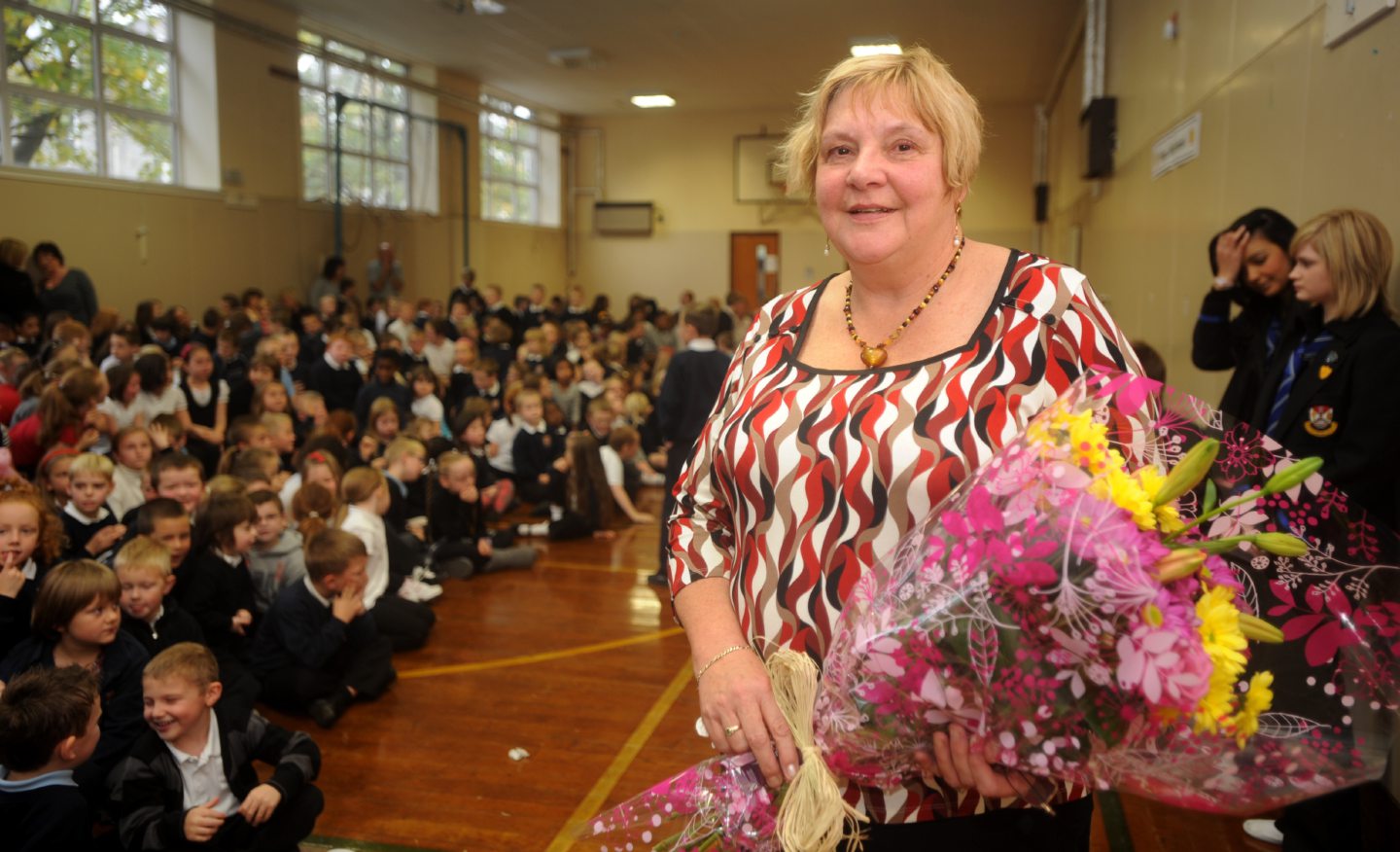 Headteacher Maureen Robertson holding flowers she received from pupils ahead of her retirement.