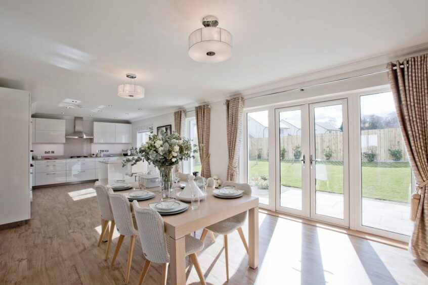 An open plan kitchen and dining area with glass patio doors leading out to the garden.