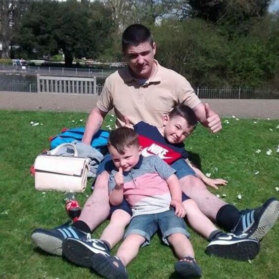 Robert Bromell pictured playing on the grass with his sons Kaiden and Kai. 