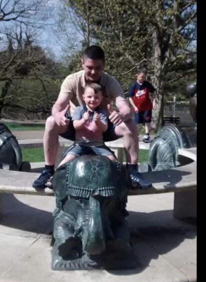 Mr Bromell pictured playing with his kids near a statue. 