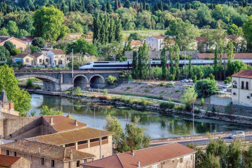 Towns and cities go by in the blink of an eye on France's high-speed TGV trains. This one is passing over a bridge on the River Orb at Beziers, Herault, in the south of France.