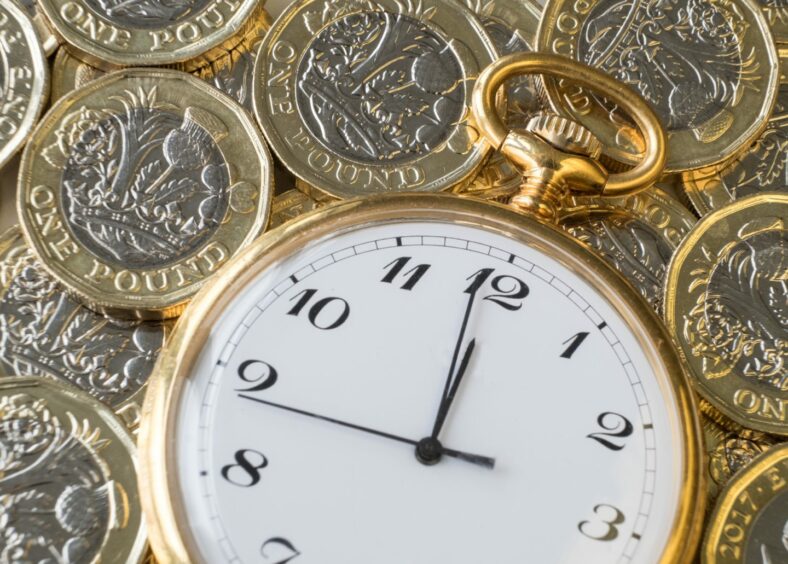 Time and money, gold watch near midnight on a pile of coins.