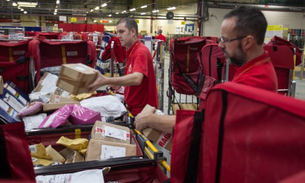 Two Royal Mail workers sorting post in a sorting room.