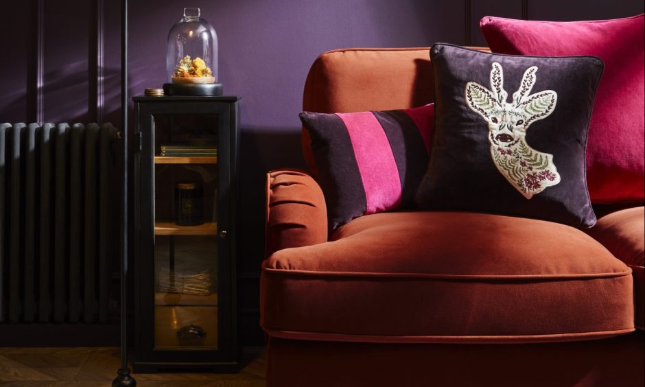 Stylish orange velvet sofa topped with a roe deer cushion and other accessories, ideal for your autumn home decor.