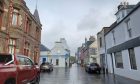 A rain-washed street in Stornoway with a faint rainbow visible in the sky.