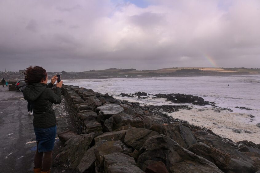 Woman taking pictures of the storm in Aberdeenshire.