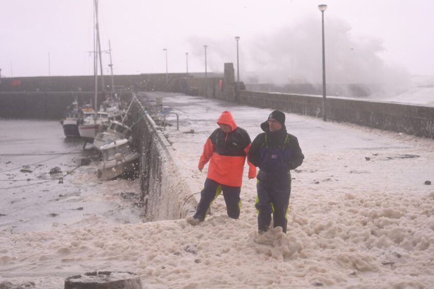 People braving the sea foam at Stonehaven harbour.
