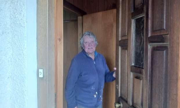 Anne Farquharson standing at front door of house.