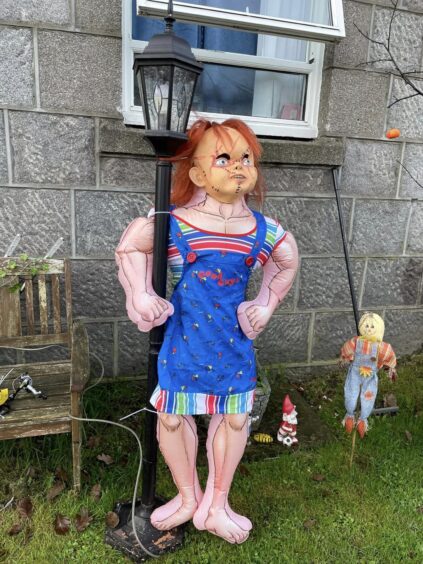 A chucky doll is in the Halloween display. 