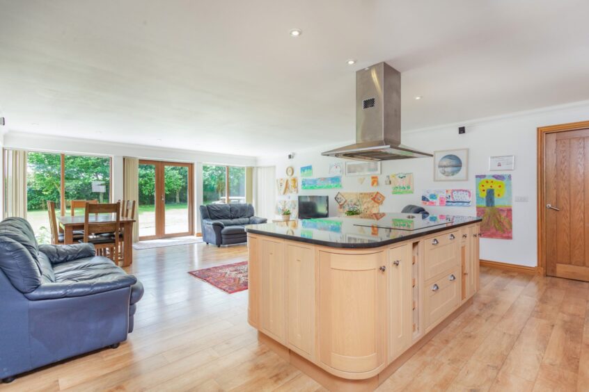 An open plan living, dining and kitchen area with glass patio doors leading out to the Aberdeenshire property's garden