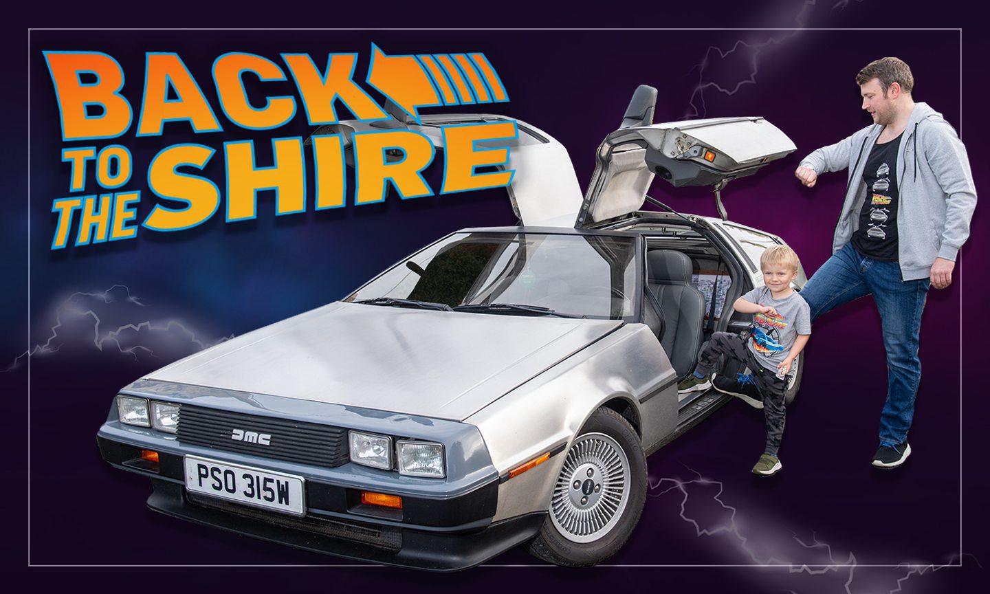 John McAulay and son Fraser check their watches next to the DeLorean with lettering saying "Back to the Shire".
