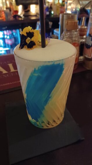 White cocktail with stripe of blue "paint" inside the glass.
